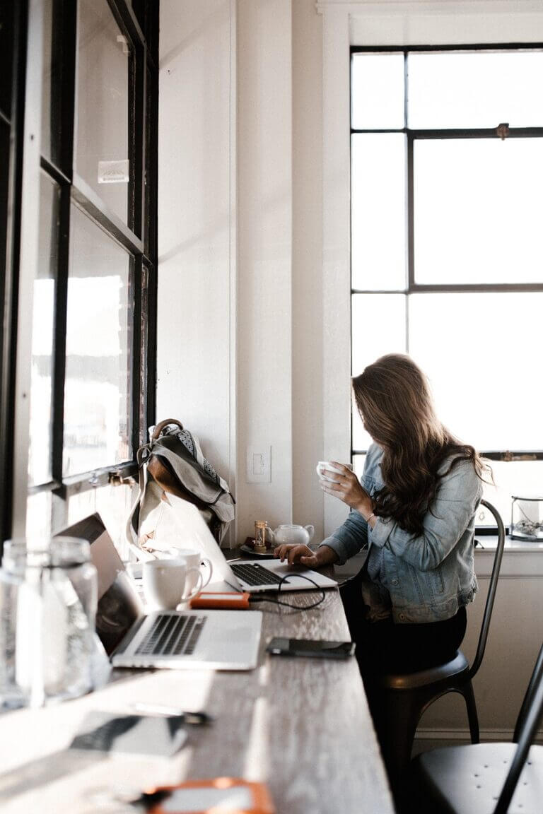 une femme devant un ordinateur avec un café à la main